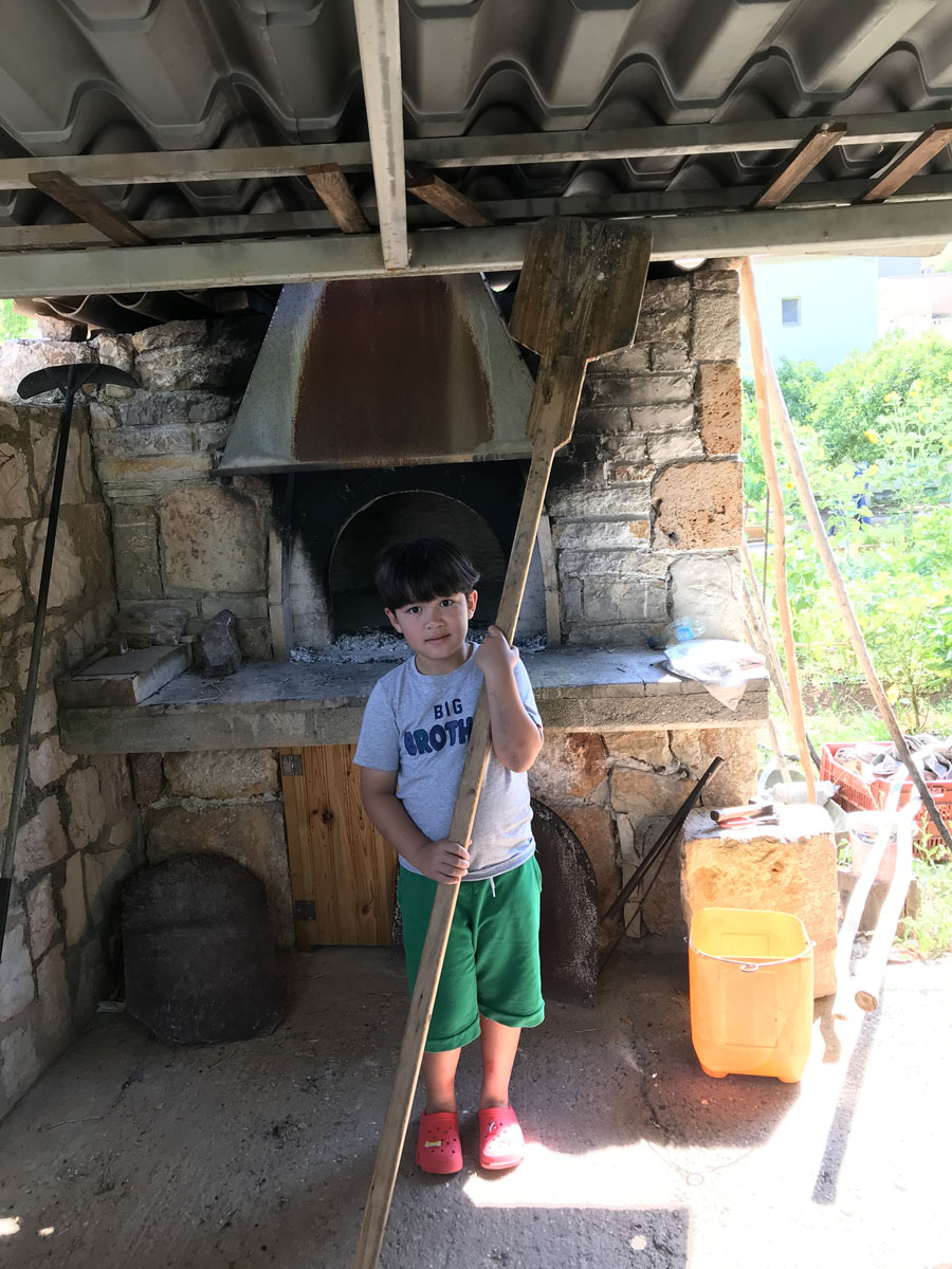 2024 @ Arcadia, Peloponnese, Greece Using the baker's shovel (fournóftyaro) to take the bread out of the traditional Greek firewood oven (foúrnos)